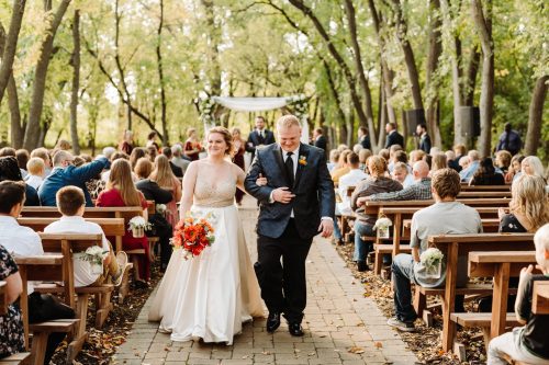Seasonality of the space is important when choosing a venue. This photo depicts a bride and groom walking down the aisle at the Natural Cathedral at Bold North Cellars.
